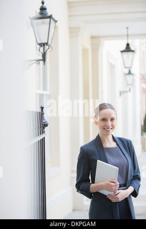 Businesswoman holding tablet on city street Stock Photo