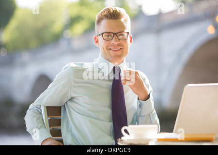 Businessman smiling at sidewalk cafe Stock Photo