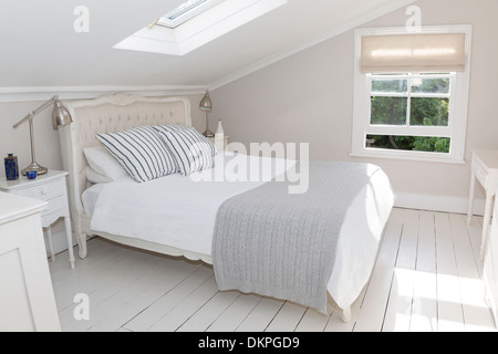 Bed in whitewashed attic bedroom Stock Photo