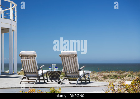 Lounge chairs on patio overlooking ocean Stock Photo