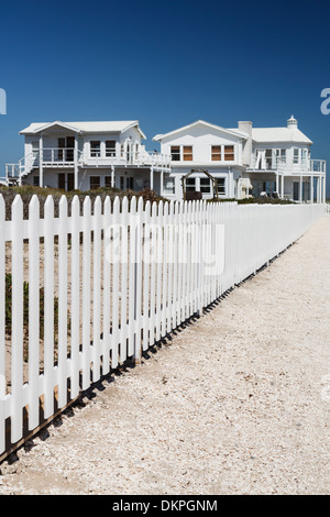 White picket fence leading to beach houses Stock Photo