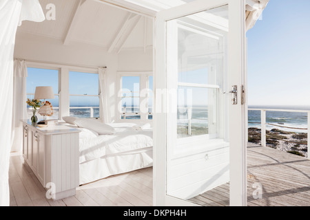 White bedroom overlooking ocean Stock Photo