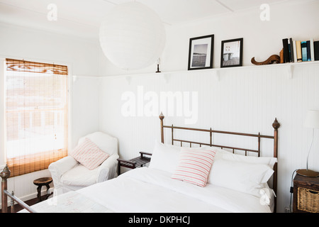 Shelf above bed in white bedroom Stock Photo