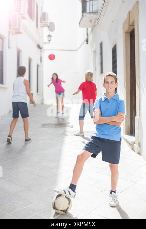 Boy holding soccer ball in alley Stock Photo
