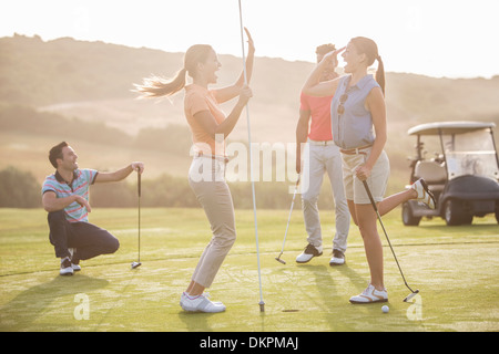 Women high fiving on golf course Stock Photo