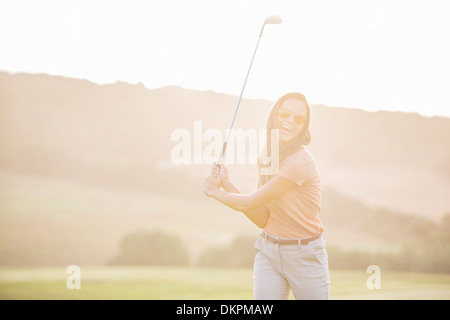 Woman playing golf on course Stock Photo