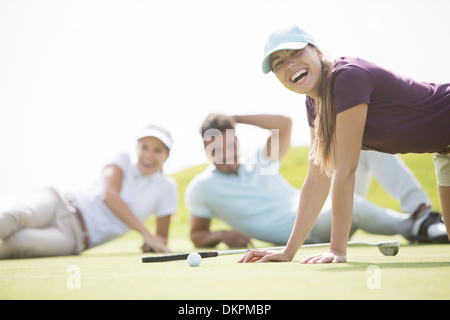 Friends laying and laughing on golf course Stock Photo