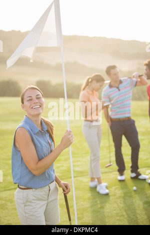 Smiling woman holding golf flag Stock Photo