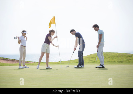 Friends putting on golf course Stock Photo