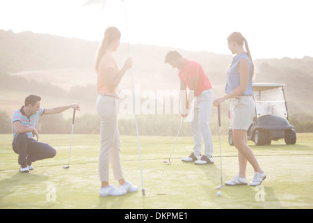 Friends playing golf on course Stock Photo