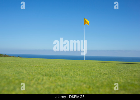 Flag on golf course overlooking ocean Stock Photo