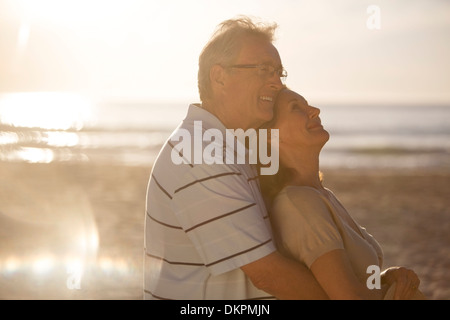 Older couple hugging on beach Stock Photo