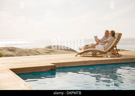 Older couple relaxing by pool Stock Photo