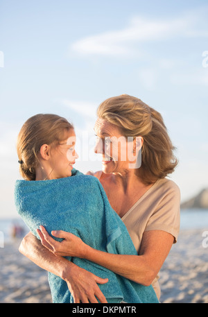 Older woman holding granddaughter on beach