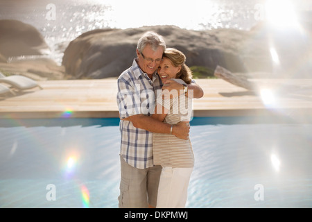 Older couple hugging by pool Stock Photo