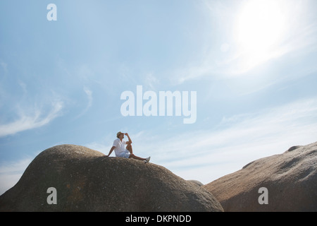 Man sitting on rock formation Stock Photo
