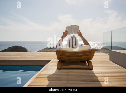 Older man reading by pool Stock Photo