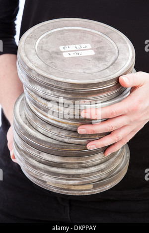 Female hands holding a pile of metal film cans. Selective focus on top can. Stock Photo