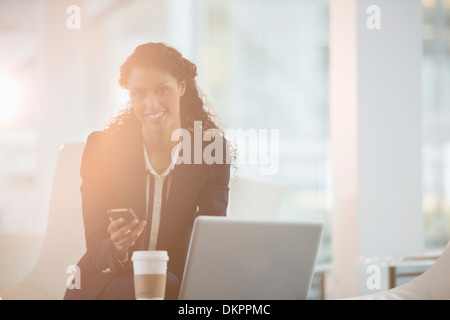 Businesswoman using cell phone in office Stock Photo