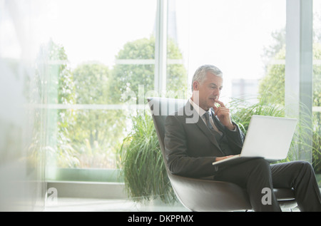 Businessman using laptop in lobby Stock Photo