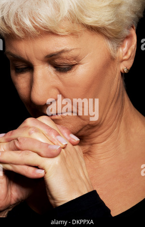 Portrait of old woman praying. Over black background.  Stock Photo