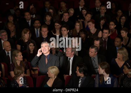 Man talking on cell phone in theater audience Stock Photo