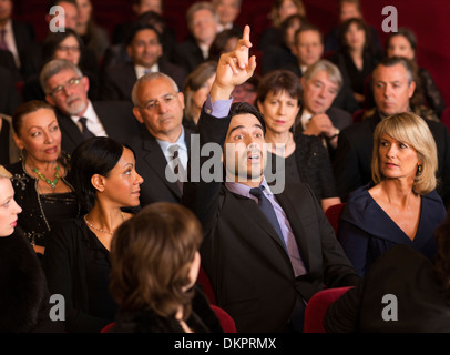 Man raising hand in theater audience Stock Photo