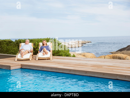 Senior couple relaxing at poolside Stock Photo