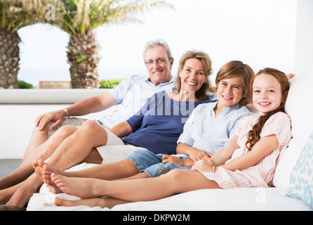Older couple and grandchildren relaxing on sofa Stock Photo