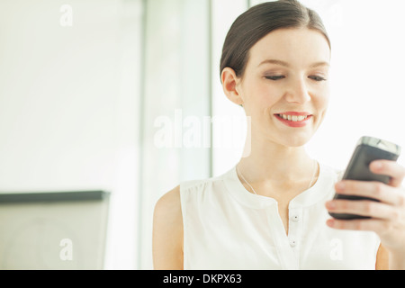 Businesswoman using cell phone in office Stock Photo