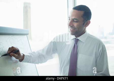 Businessman writing on whiteboard in office Stock Photo