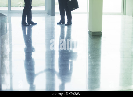 Reflection of businessmen shaking hands in office lobby Stock Photo