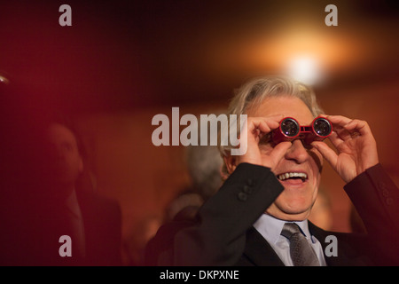 Close up of man using opera glasses in theater Stock Photo