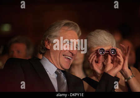 Close up of smiling couple using opera glasses in theater audience Stock Photo