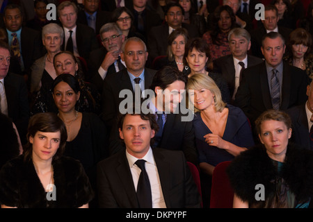 Couple talking among serious theater audience Stock Photo