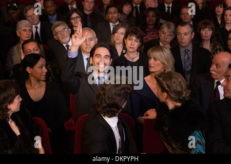 Man raising hand in theater audience Stock Photo