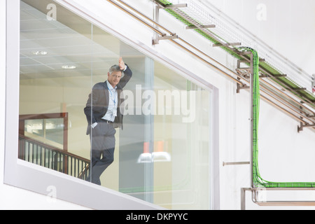 Supervisor leaning on glass window in warehouse Stock Photo
