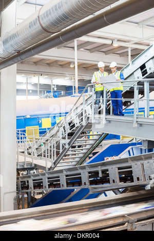 Workers looking at blueprints in recycling center Stock Photo