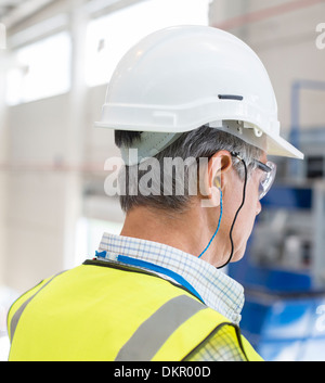 Worker wearing hard hat and ear plugs Stock Photo