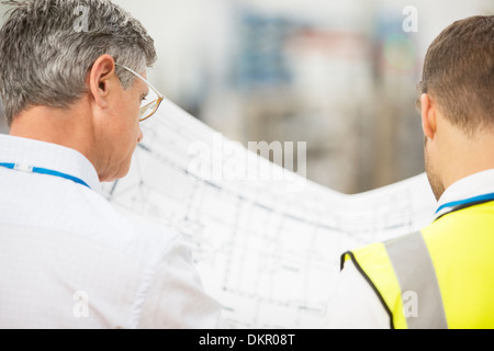 Workers reading blueprints in warehouse Stock Photo