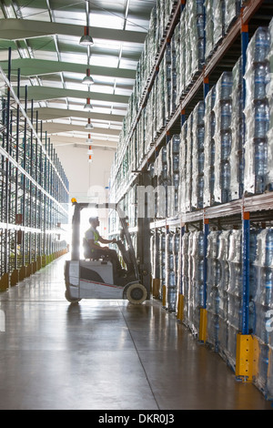 Worker operating forklift in warehouse Stock Photo