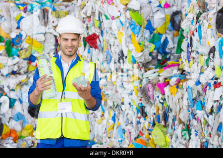 Worker holding compacted plastic bottle in recycling center Stock Photo