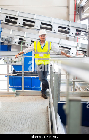 Worker leaning on platform railing in factory Stock Photo