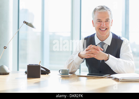 Businessman smiling at desk in office Stock Photo