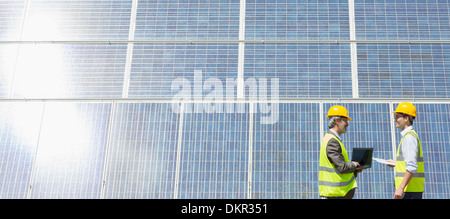 Workers examining solar panels in rural landscape Stock Photo