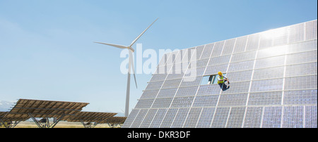 Worker examining solar panel in rural landscape Stock Photo