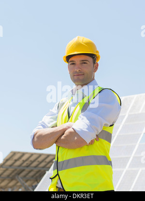 Worker standing by solar panels in rural landscape Stock Photo