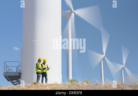 Workers talking by wind turbines in rural landscape Stock Photo