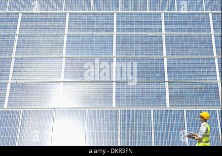 Worker examining solar panel in rural landscape Stock Photo