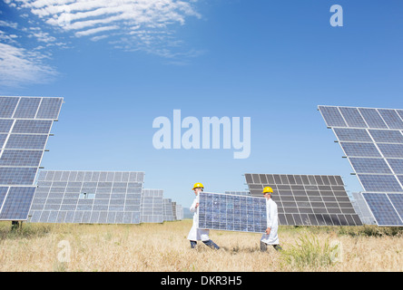 Scientists carrying solar panel in rural landscape Stock Photo